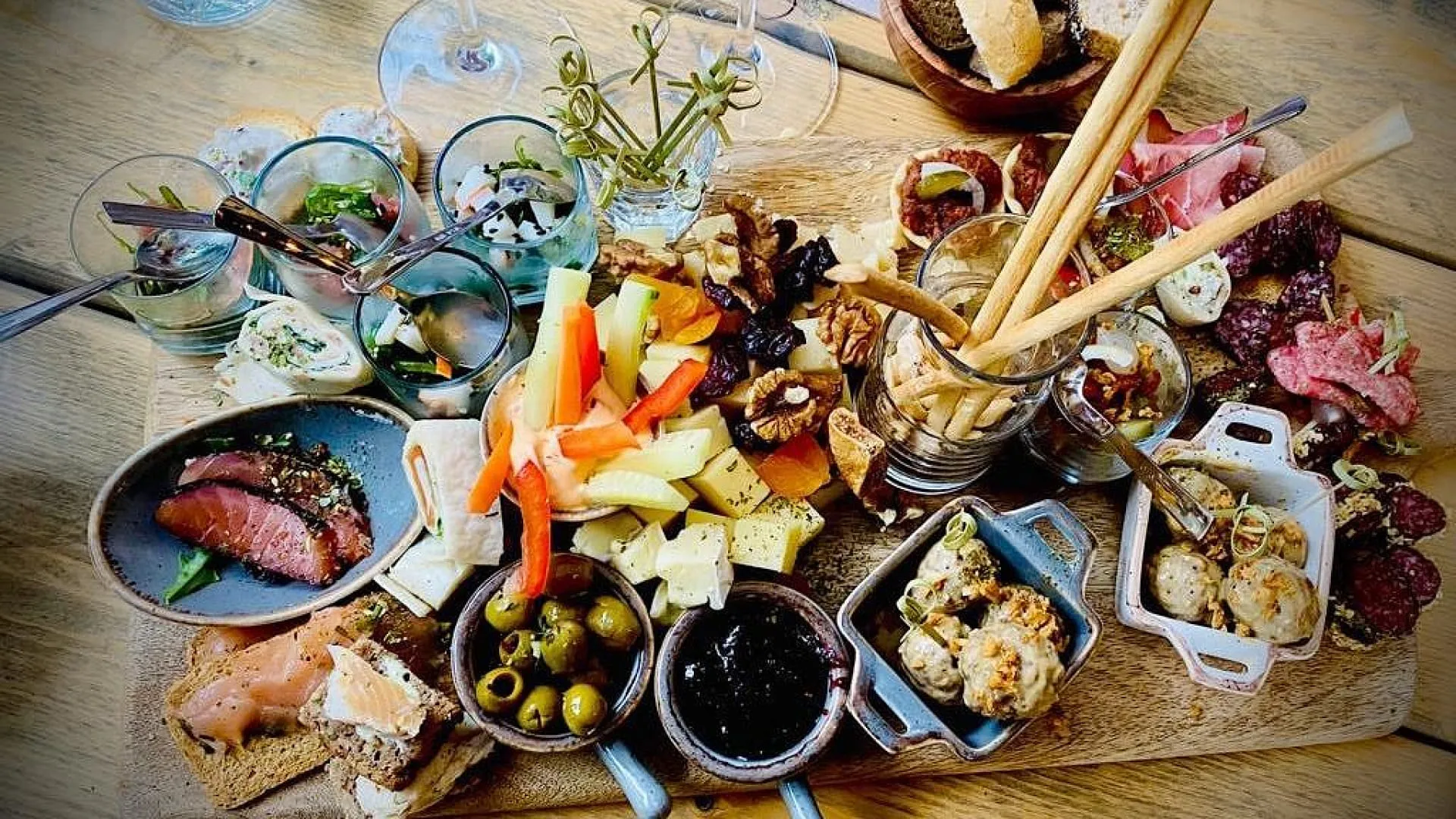 Ein Holzbrett mit einer Vielzahl von Gerichten, darunter Fleisch, Gemüse und Brot.