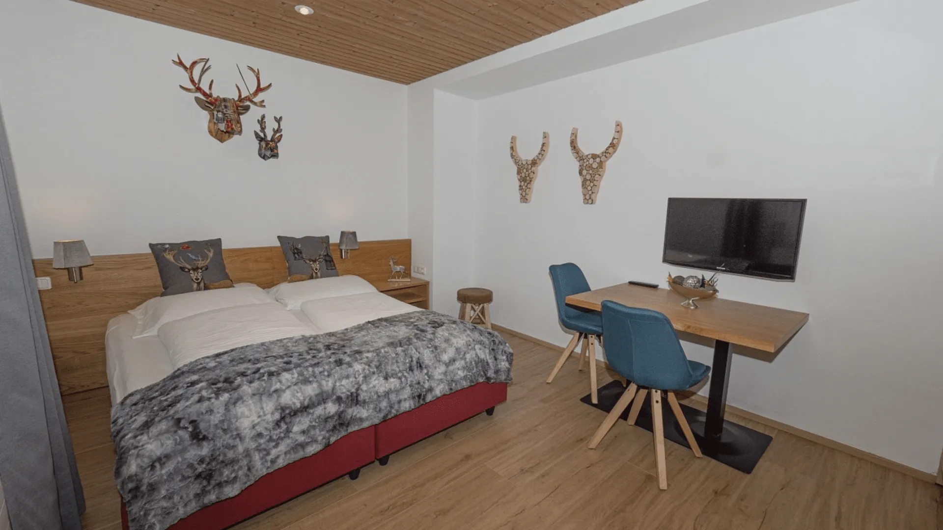 Gemütliches Schlafzimmer mit Doppelbett, Schreibtisch und Fernseher.