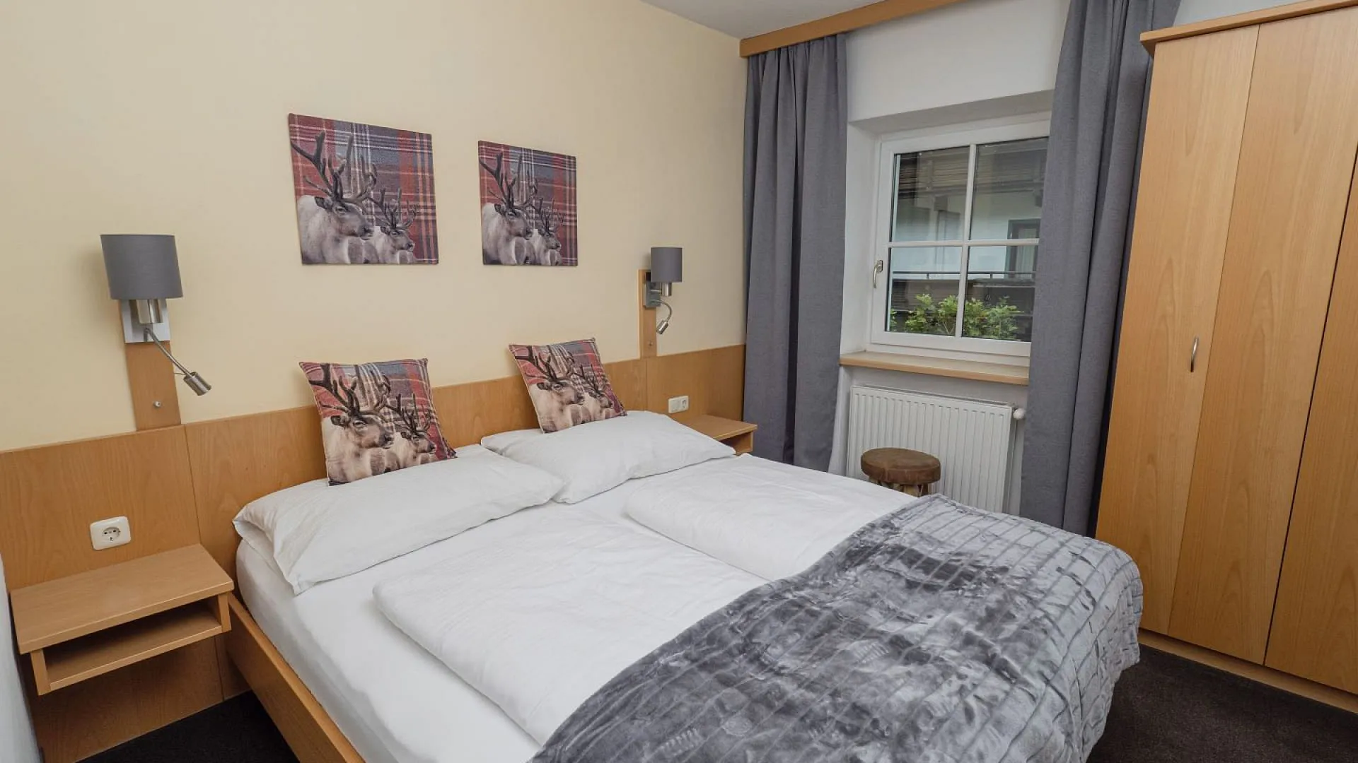 Helle Schlafzimmer mit zwei Betten, grauer Decke und Holzschrank