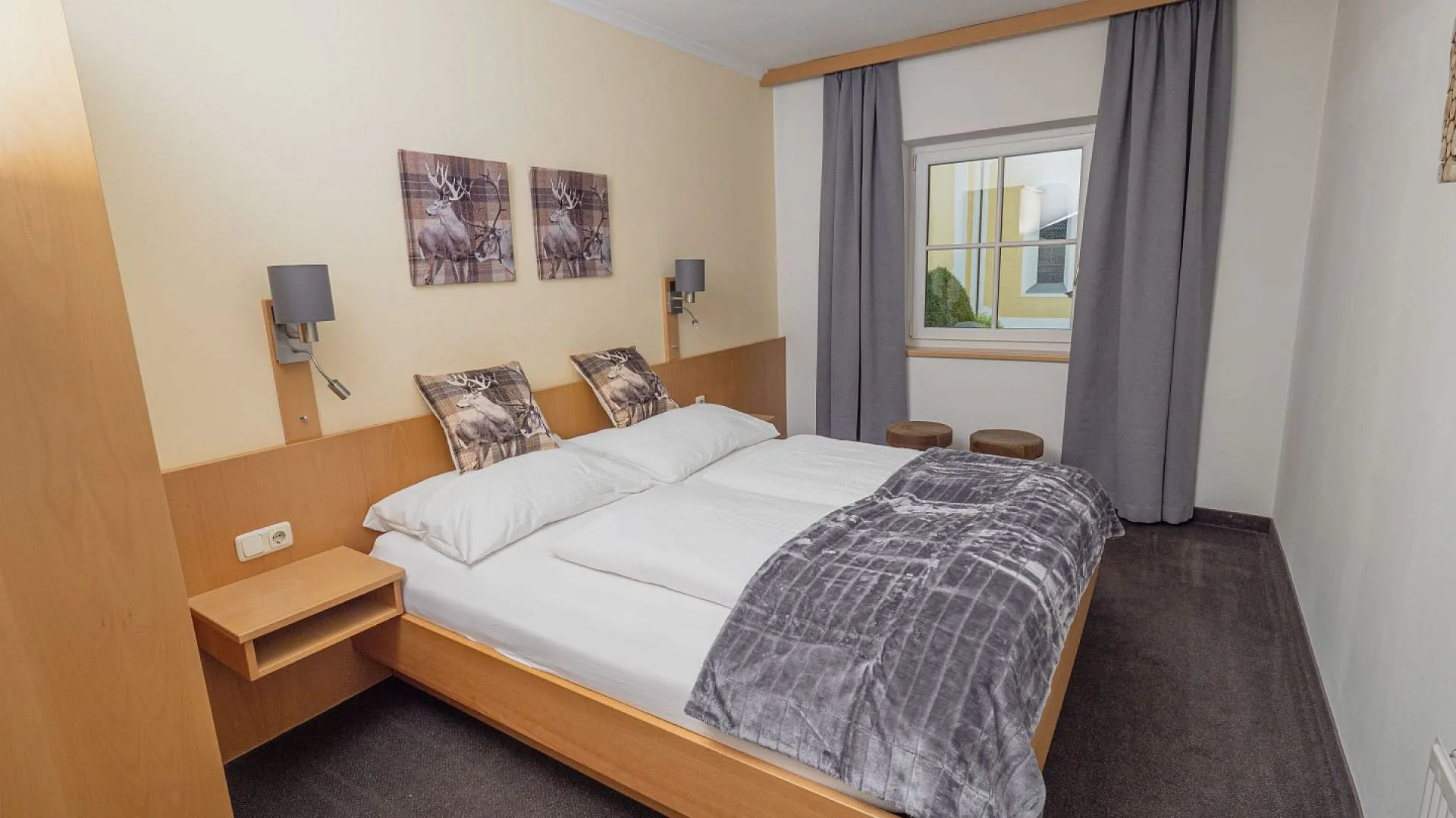 Gemütliches Schlafzimmer mit Holzmobiliar und zwei Betten, Fenster mit Gardinen.
