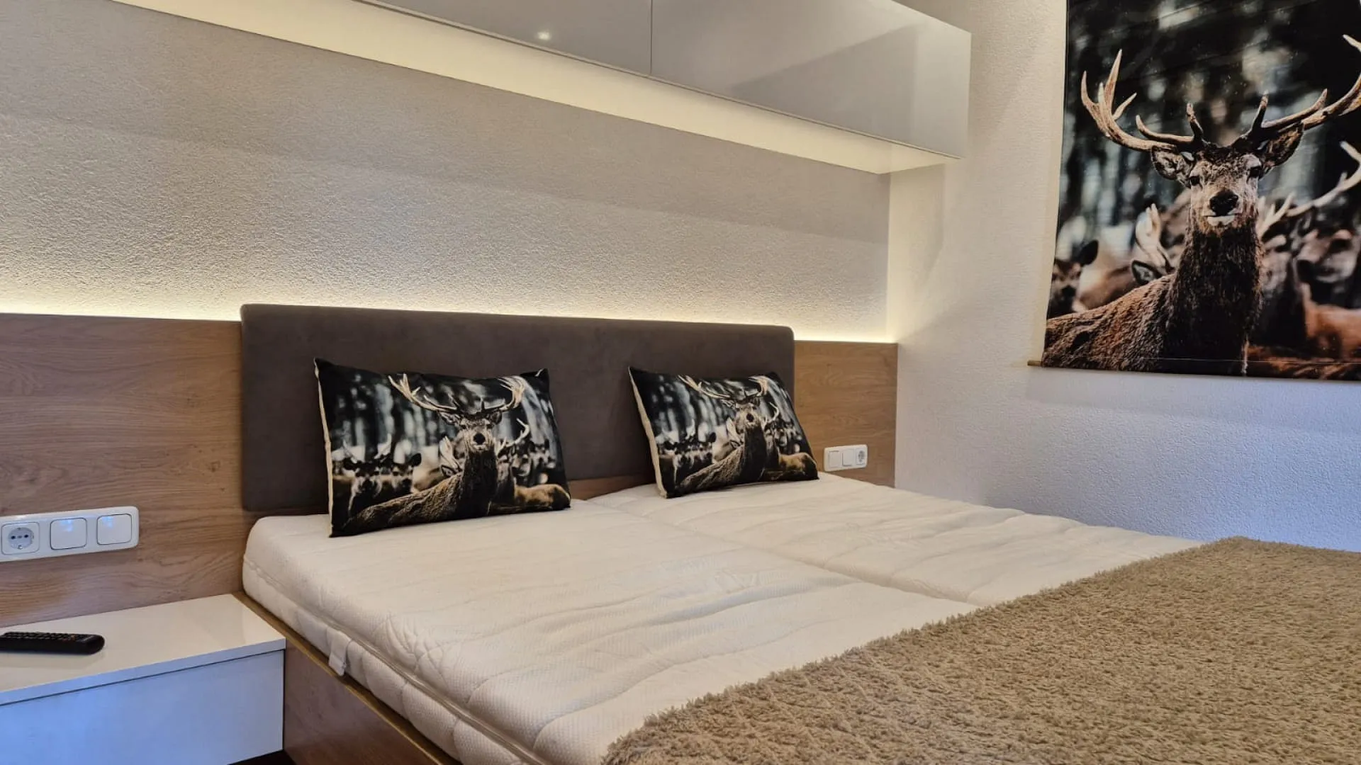 Schlafzimmer mit einem Bett und Kissen, Wandschmuck eines Rehs